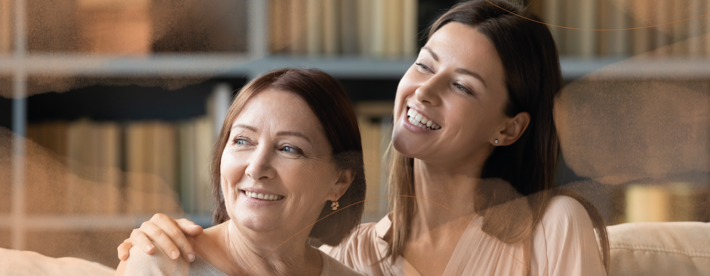 Older and younger women arm in arm, smiling 