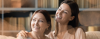 Older and younger women arm in arm, smiling 